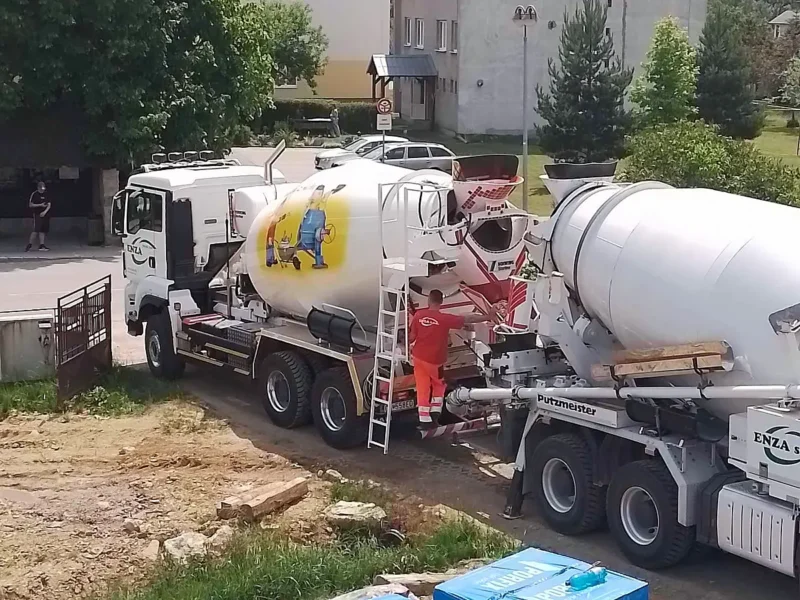 Autodomiešavač pri bytovom dome, pracovník na rebríku pri miešačke