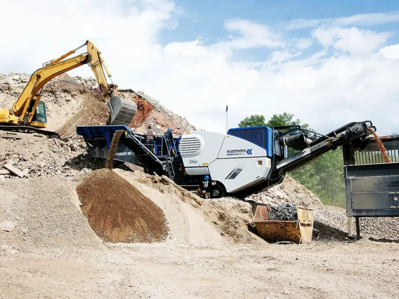 Mobilný čeľusťový drvič Kleemann a rýpadlo pri hromade rozdrveného materiálu