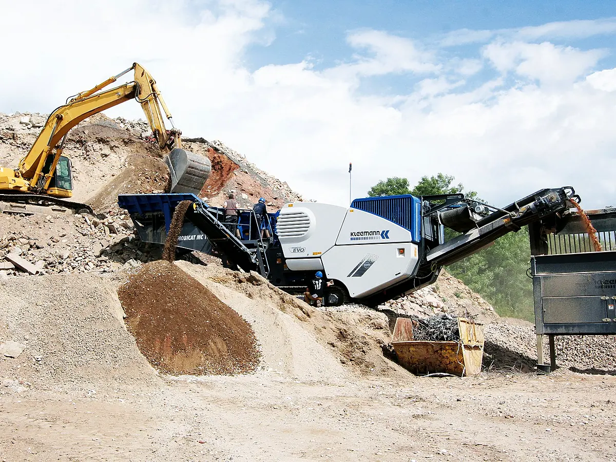 Mobilný čeľusťový drvič Kleemann a rýpadlo pri hromade rozdrveného materiálu
