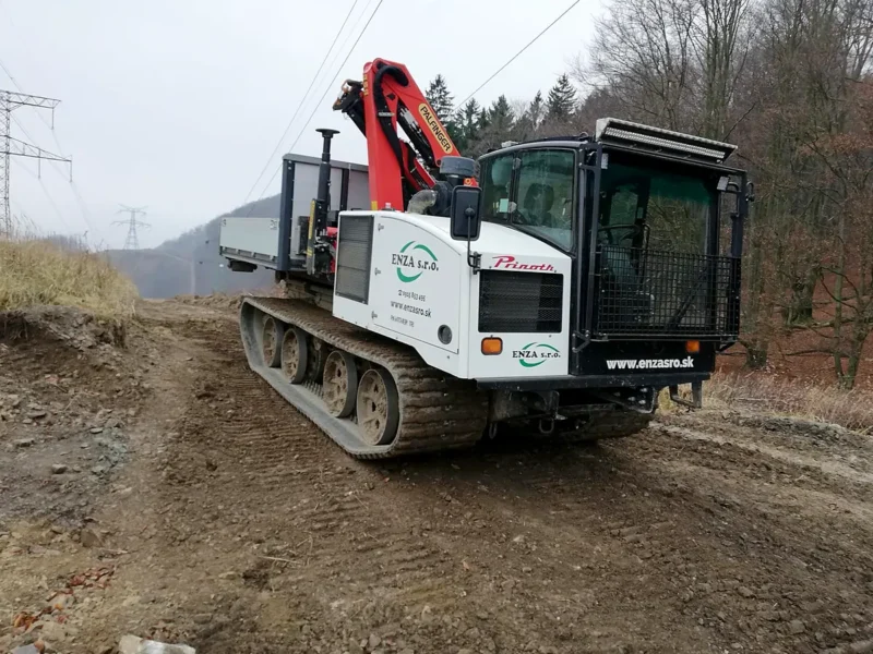 Biele pásové vozidlo s hydraulickou rukou a označením ENZA na lesnej ceste