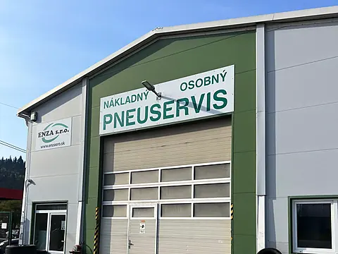 Building of a lorry and car tyre service with signage and a gate, tyres stacked in front of the entrance