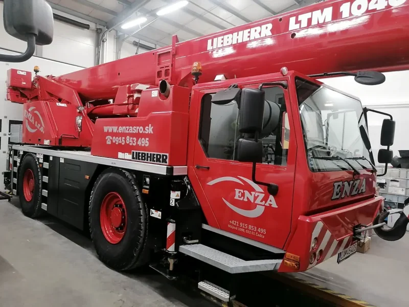 Červený autožeriav Liebherr LTM 1040 s nápisom ENZA zaparkovaný v hale